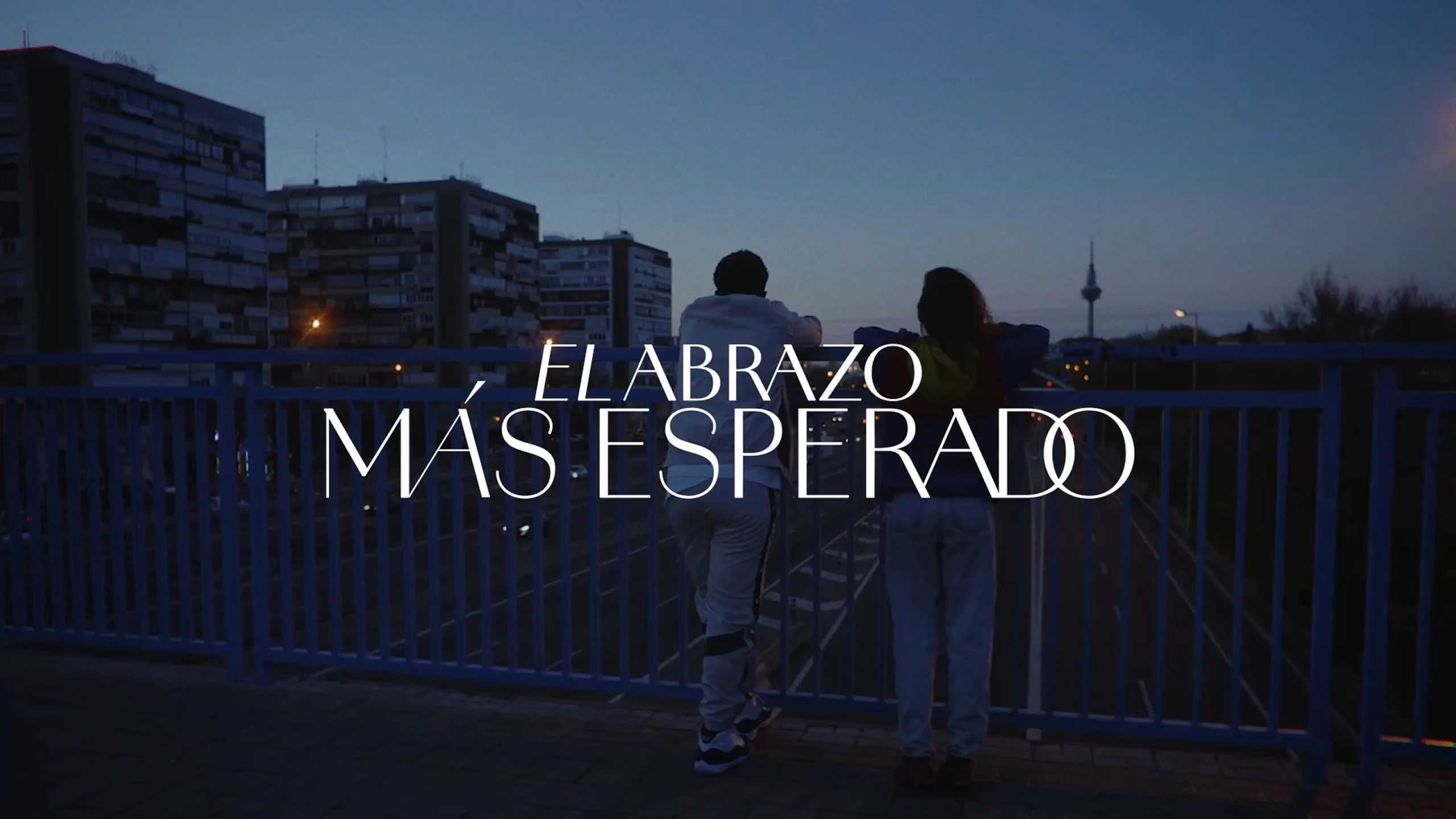 Campaign visual showing two people from behind on a bridge, alongside the title The Most Awaited Embrace.